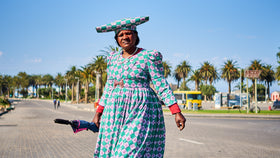 Eine einheimische Frau in traditioneller Kleidung überquert eine Strasse.