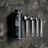 Olivenöldose liegend neben kleiner werdenden Löffeln.