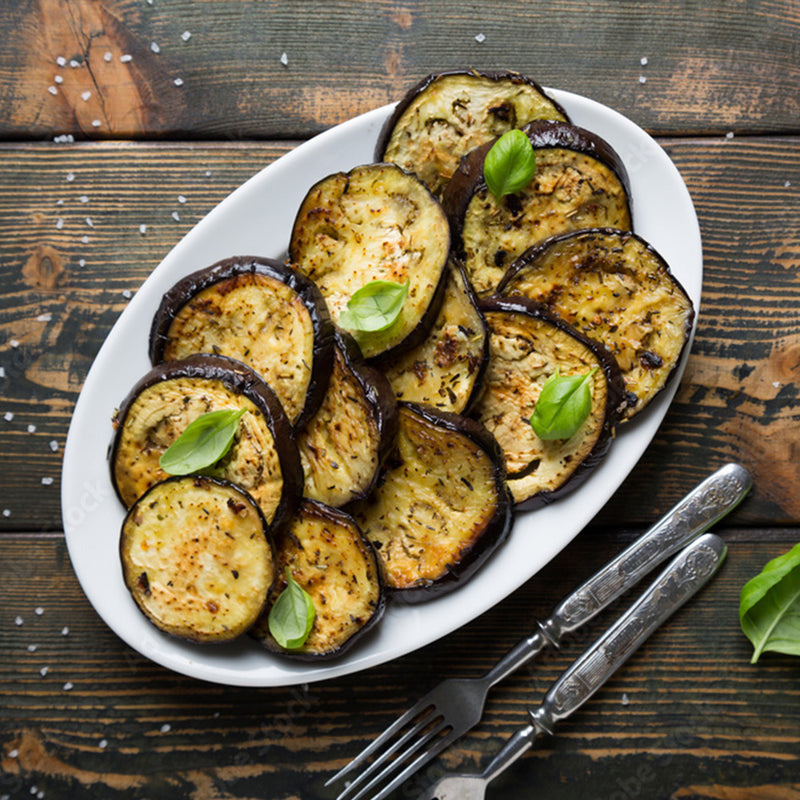 Gebratene Auberginenscheiben mit Alter Grieche gewürzt auf Teller, angerichtet auf rustikalem Holztisch.