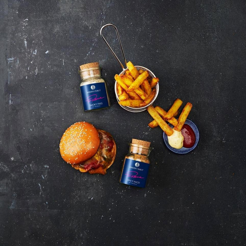 Ein saftiger Burger sowie knusprige Pommes aus der Vogelperspektive, daneben Ankerkraut Smoky Fries sowie Spicy Hack im Korkenglas.