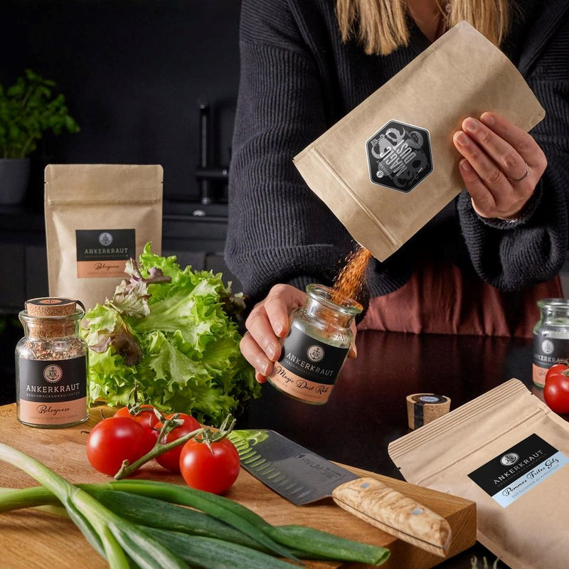 Magic Dust Rub wird von einer Frau von einem Nachfüllbeutel ins Korkenglas umgefüllt.