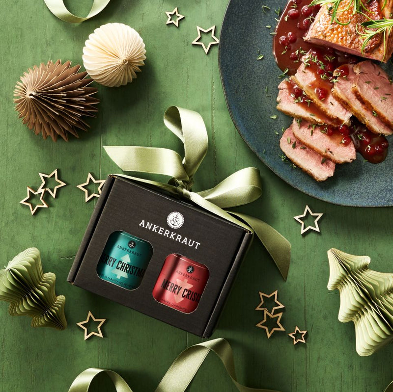 Merry Christmas Gewürz-Box aus schwarzem Karton neben weihnachtlicher Deko und einem Teller Gänsebraten.