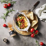 Gegrillter Schafskäse mir Gemüse in Alufolie auf einem Holzbrett.