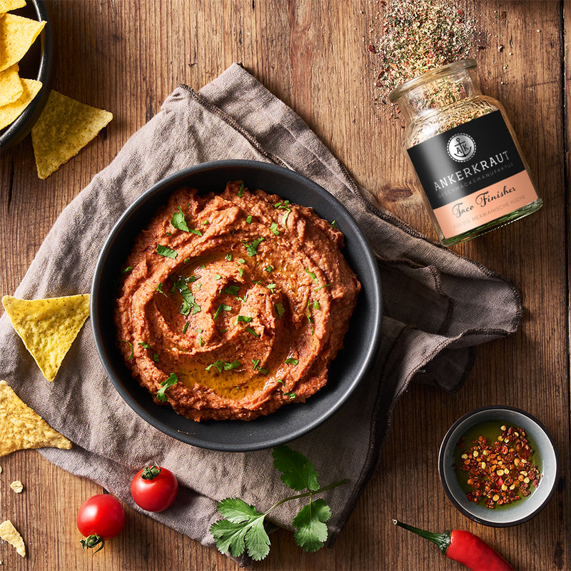 Ankerkraut Taco Gewürz im Korkenglas von oben, neben einer Schale mit Dip und Nacho Chips.