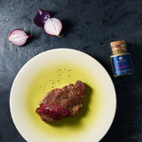 Entrecote mit Zwiebelkompott auf einem weißen Teller angerichtet.